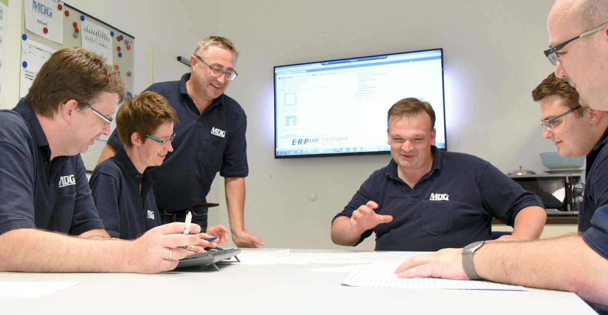 Mitarbeiter besprechen Pläne vor einem Bildschirm mit Konstruktionssoftware