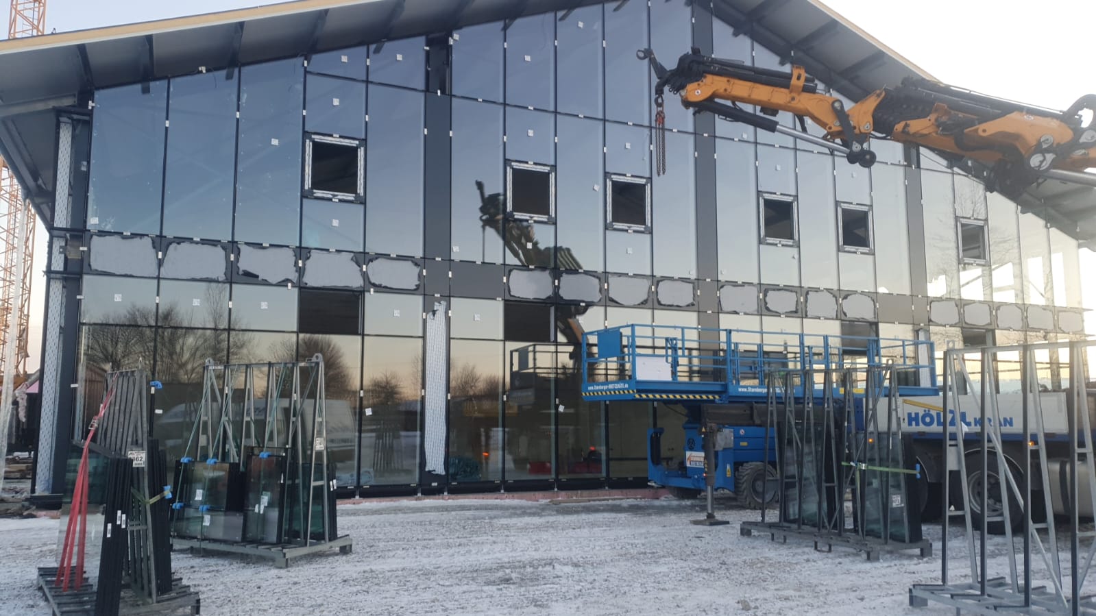 Glasscheiben werden mit einem Kran in eine Pfosten-Riegel-Fassade eingesetzt
